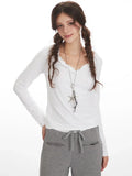 Woman posing in white long-sleeve top and grey wide-leg fleece pants