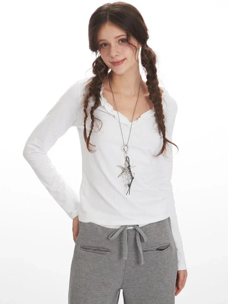 Woman posing in white long-sleeve top and grey wide-leg fleece pants