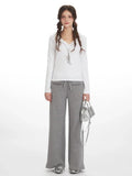 Woman wearing white long-sleeve top and grey wide-leg fleece pants