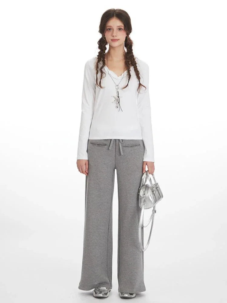 Woman wearing white long-sleeve top and grey wide-leg fleece pants