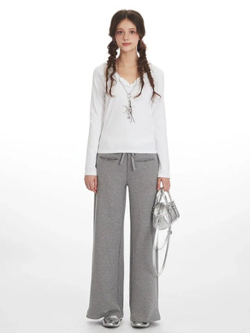 Woman wearing white long-sleeve top and grey wide-leg fleece pants