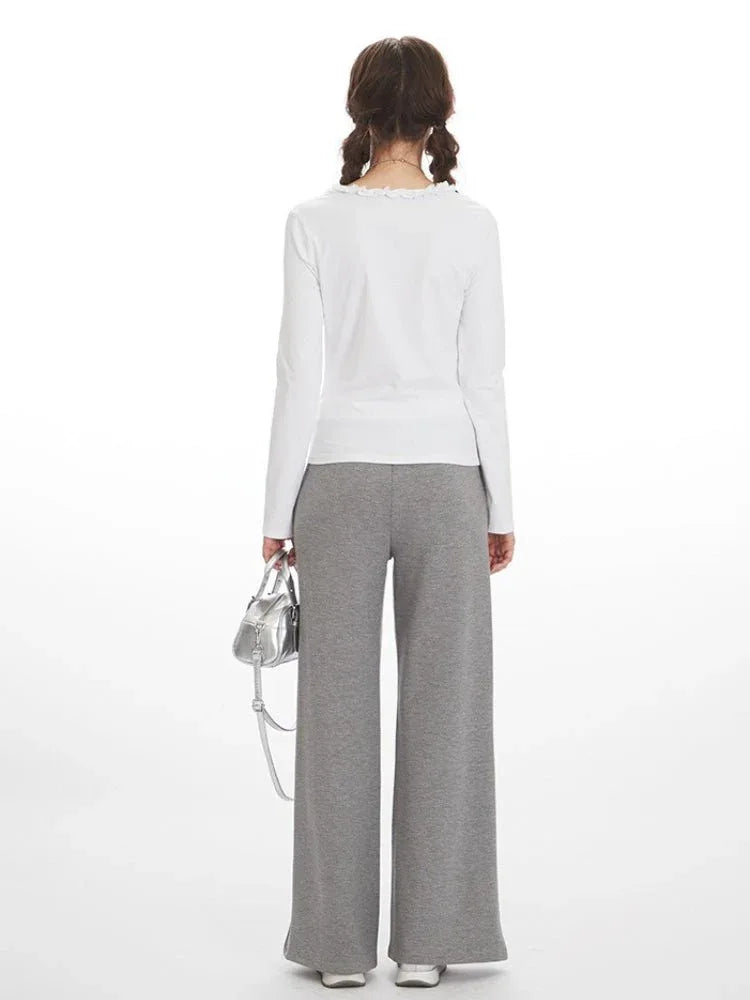 Back view of woman in white long-sleeve top and grey wide-leg fleece pants