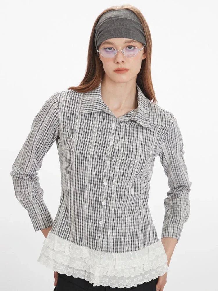 Woman in a plaid long-sleeved collared blouse with lace hem detail, styled with a grey headband and glasses.