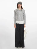 Woman wearing a long-sleeved collared blouse with a plaid pattern and white lace trim at the hem, paired with black wide-leg pants and a white handbag.