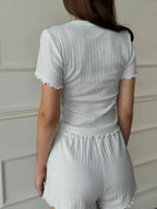 Rear view of a woman in a white short-sleeve crew neck top with ruffled hem and matching white shorts