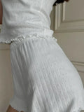 Detail of the ribbed texture and ruffled waistband on white shorts