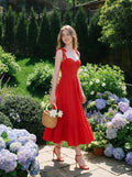 Woman in a red midi dress carrying a basket bag in a garden.