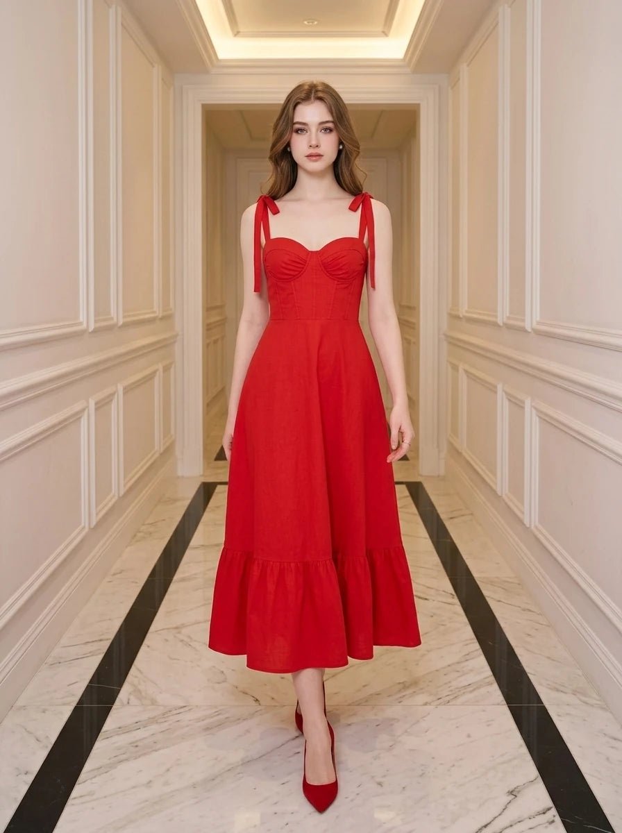 Woman in a red midi dress with sweetheart neckline and tie straps walking down a hallway.