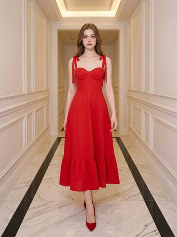 Woman in a red midi dress with sweetheart neckline and tie straps walking down a hallway.