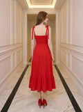 Back view of a woman in a red midi dress with smocked back and ruffle hem.