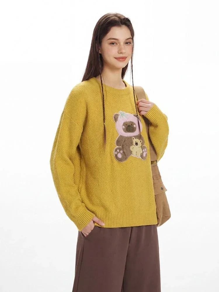 Close-up of the teddy bear appliqué on the yellow knit sweater.