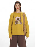 Front view of a yellow knit sweater featuring a teddy bear appliqué on the chest.