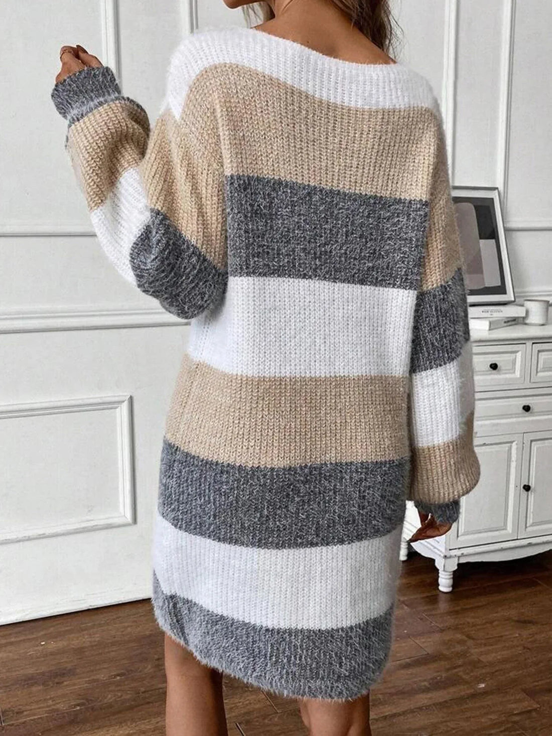 Woman in a beige, grey, and white striped knit sweater dress.