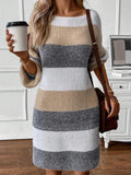 Woman holding a coffee cup while wearing a striped sweater dress.