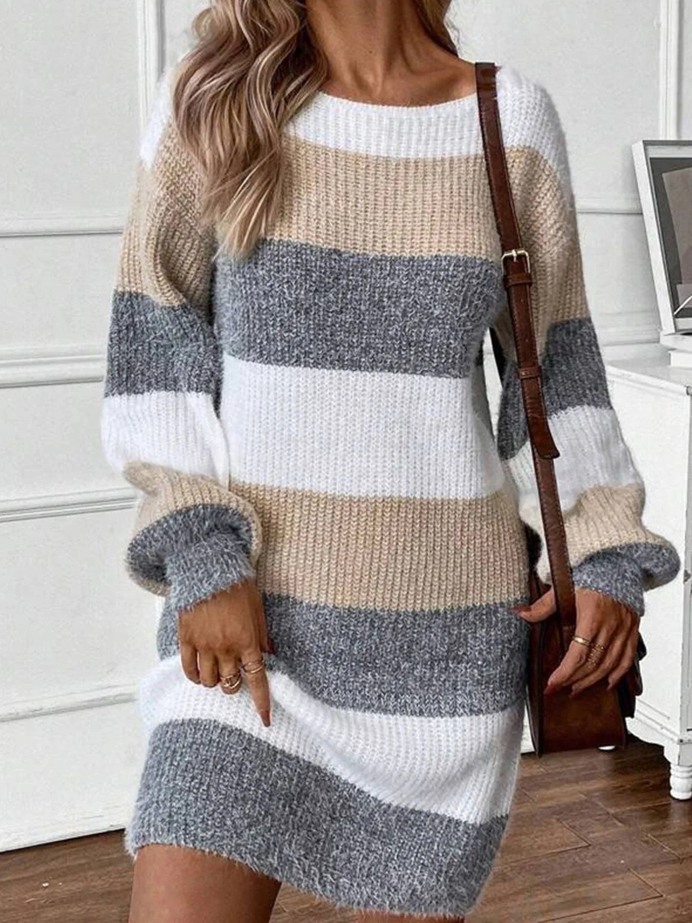 Woman in a beige, grey, and white striped knit sweater dress.