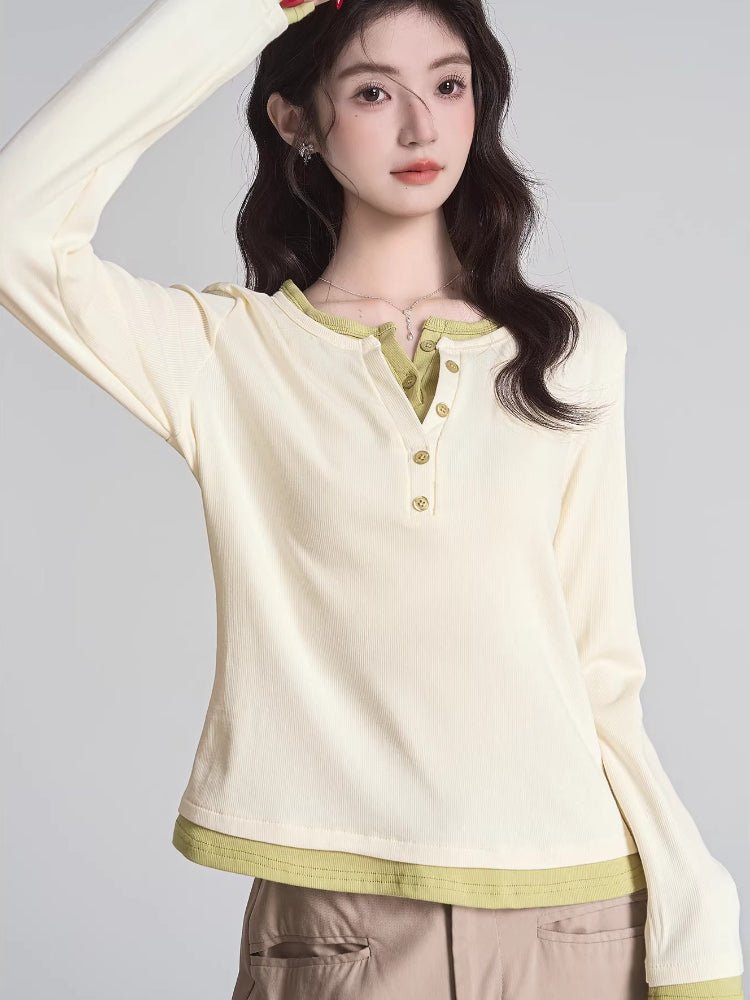Woman wearing a cream long-sleeve henley shirt with lime green trim and buttons, paired with beige trousers.