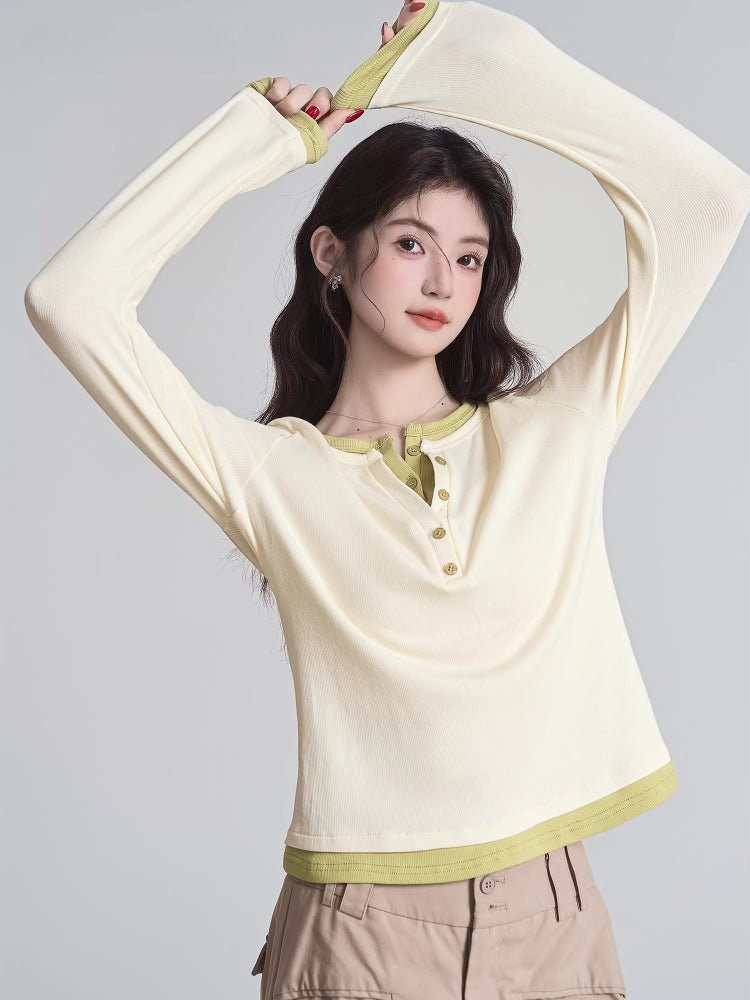 Woman in a cream long-sleeve henley shirt with lime green trim, posing with arms raised.