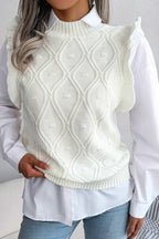 Woman wearing a white sleeveless knit vest with a diamond pattern and ruffle trim over a white button-down shirt.
