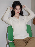 Woman posing in a cream cable knit sweater and brown wide-leg pants.