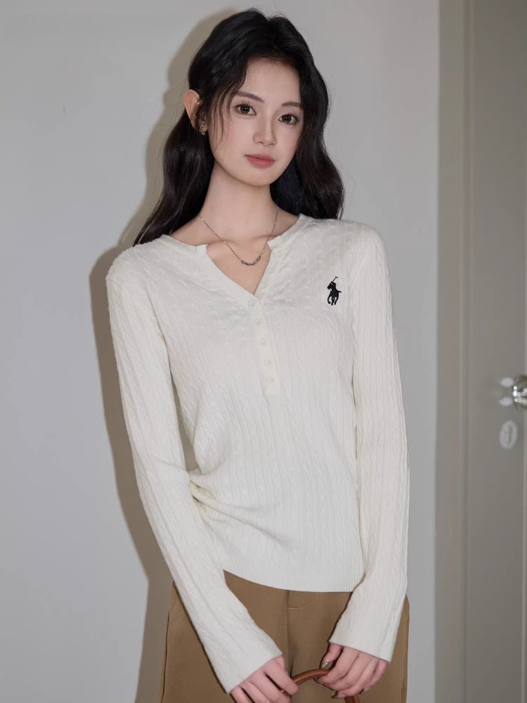Full body shot of a woman in a cream cable knit sweater and brown pants.