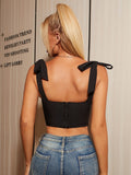 Back view of a woman in a black cropped corset top with bow shoulder straps and a zip closure.