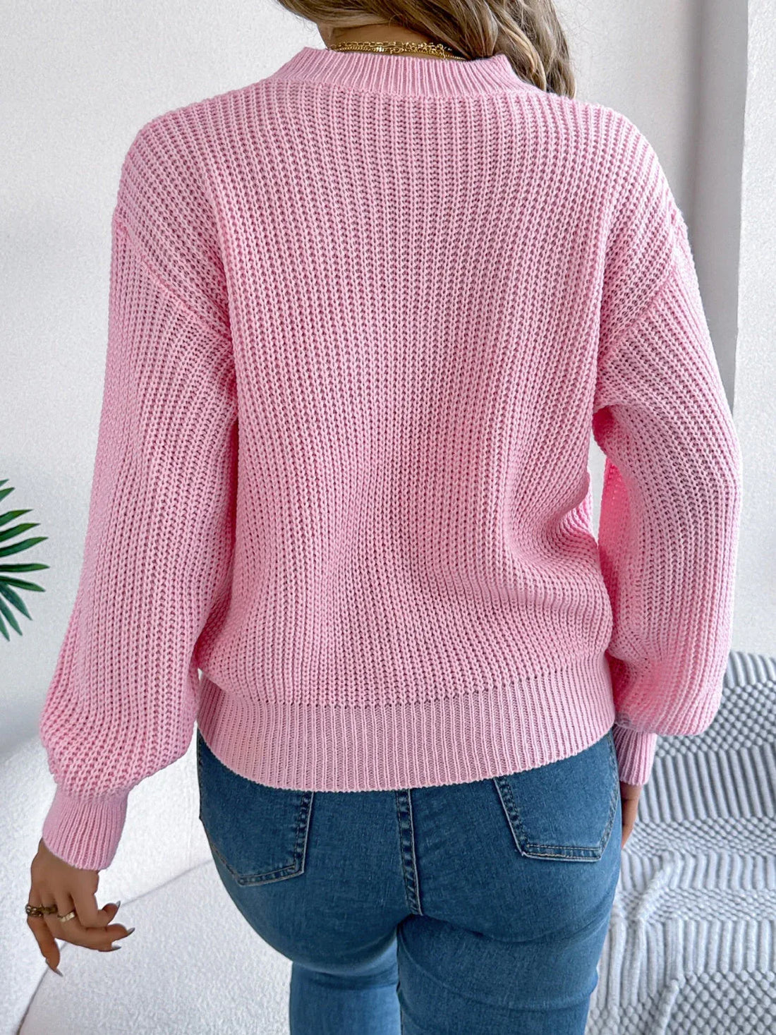 Woman wearing a pink knit sweater with a large red heart graphic and the word 'love' on the front.