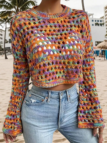 Woman wearing a multi-color cropped hollow-out knit sweater with bell sleeves and light wash jeans