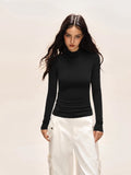 Model wearing a black long-sleeve turtleneck top and white cargo pants.