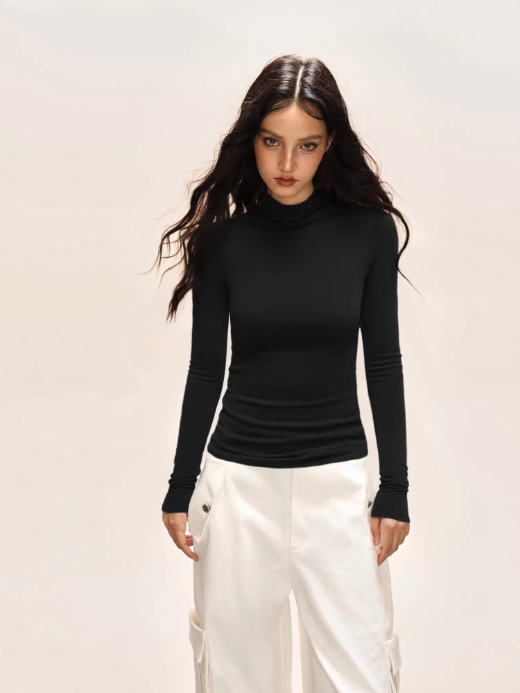 Model wearing a black long-sleeve turtleneck top and white cargo pants.