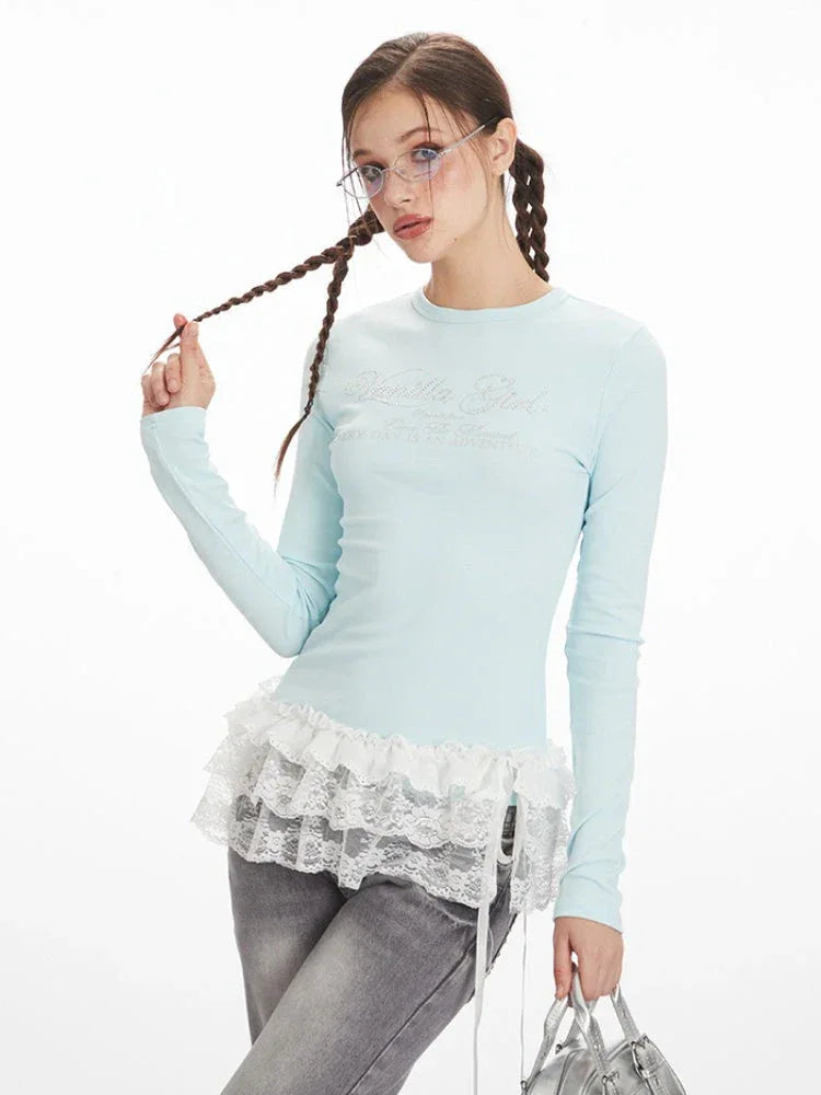 Close-up of a woman wearing a light blue long-sleeved top with white lace trim, showing the graphic print.