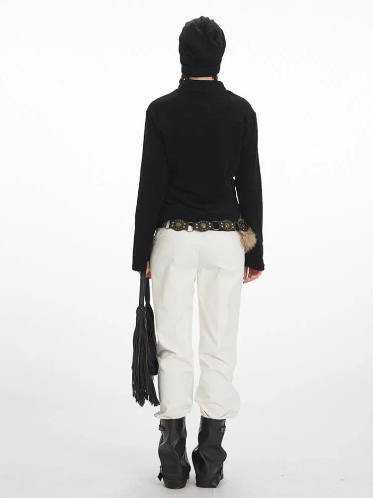 Back view of a woman in a black zip-up fleece jacket, white pants, and black boots.
