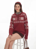 Woman sitting on a stool wearing a red knit sweater with a white Fair Isle pattern and a button placket.