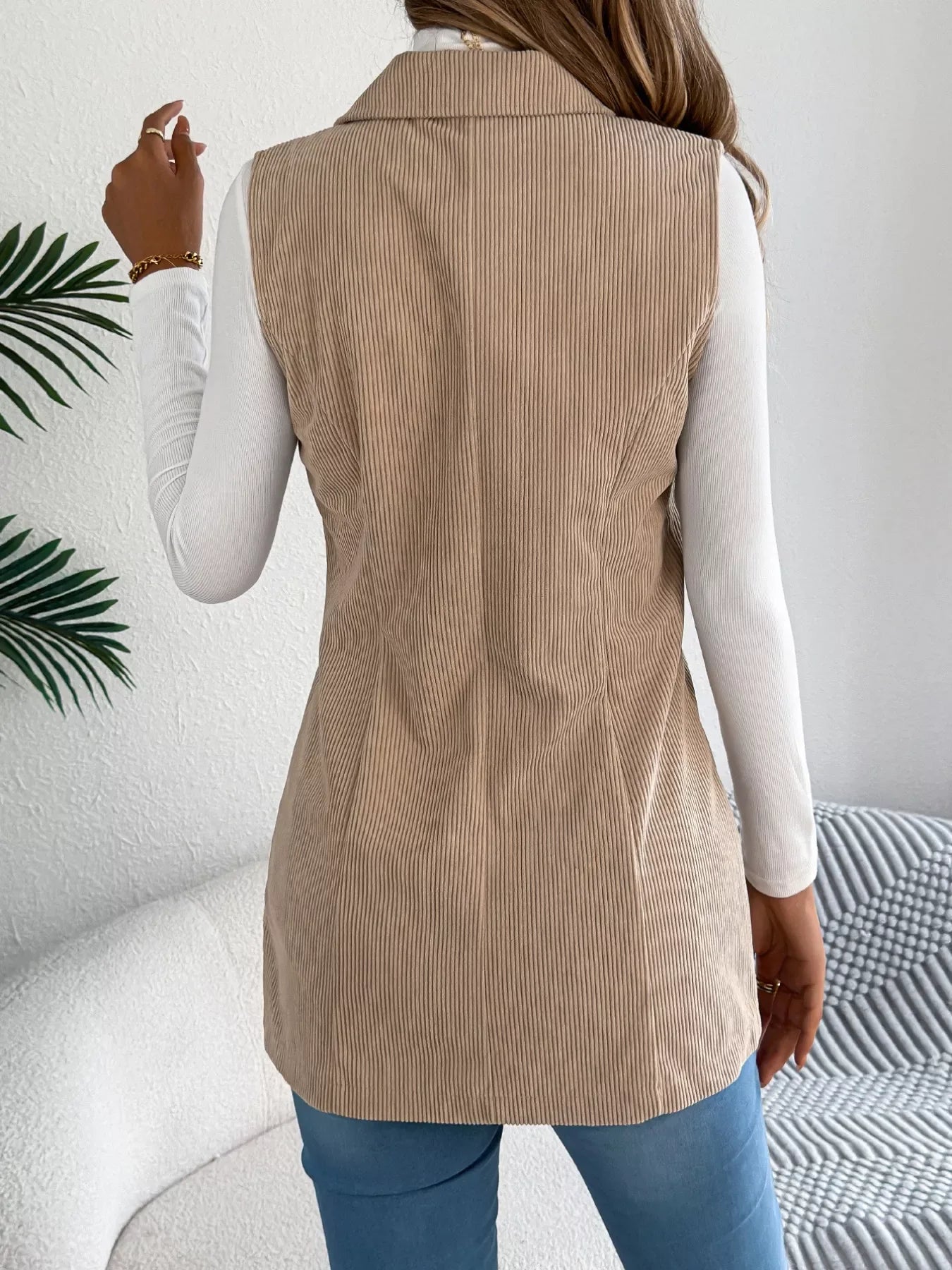 Back view of a woman in a beige corduroy longline vest.