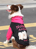 Side view of a brown and white Border Collie dog wearing a black and pink hooded dog sweatshirt, showing the graphic print on the back.