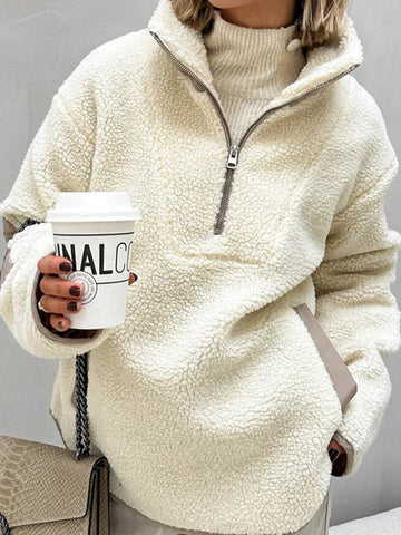 Woman wearing a cream sherpa fleece quarter-zip pullover with brown contrast trim and pockets, holding a coffee cup.