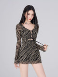 Front view of a model adjusting the tie detail on a black and gold striped sheer mesh mini dress.