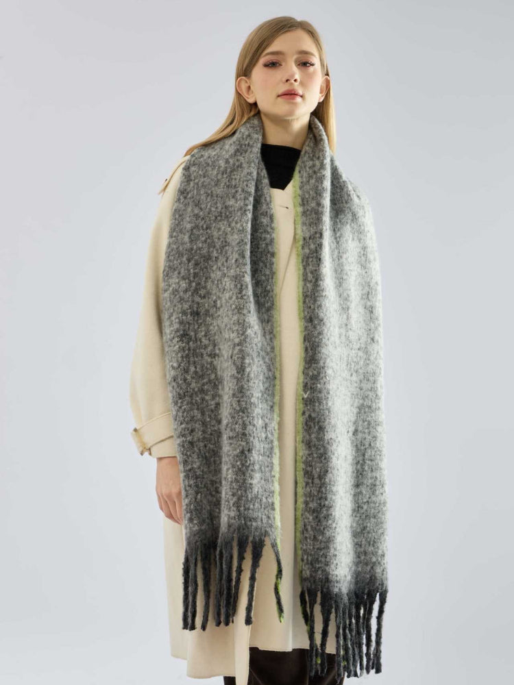 Front view of a woman showcasing a cozy, grey scarf with a vibrant green edge.