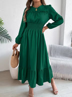 Woman wearing a long-sleeved green A-line dress with a ruched neckline and smocked waist.