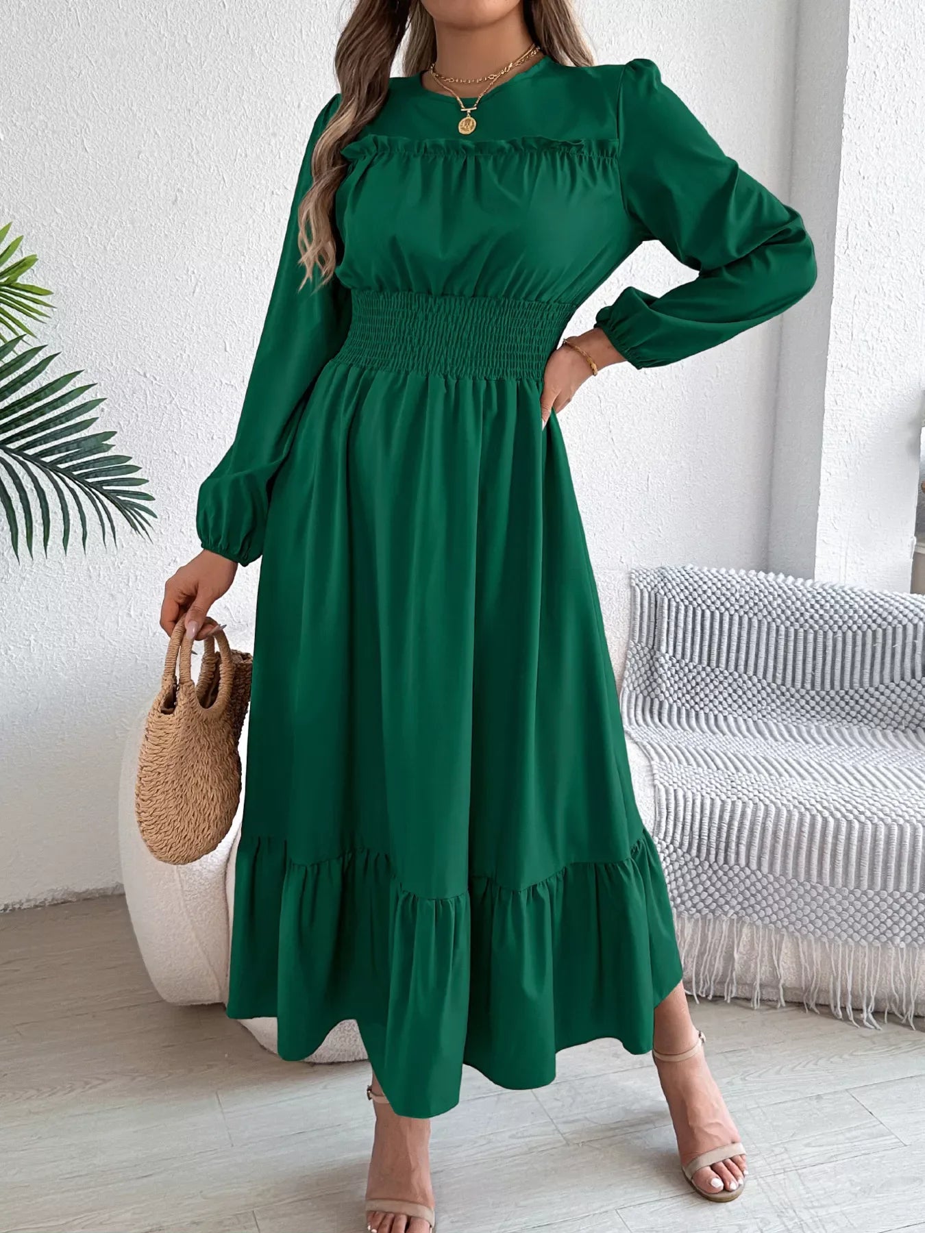 Woman wearing a long-sleeved green A-line dress with a ruched neckline and smocked waist.