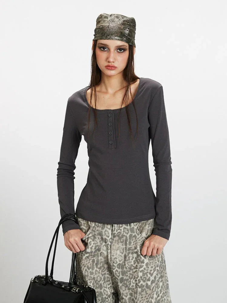 Close-up front view of a woman wearing a dark grey long-sleeve ribbed knit top with a square neckline and buttoned placket, showcasing the fabric texture.