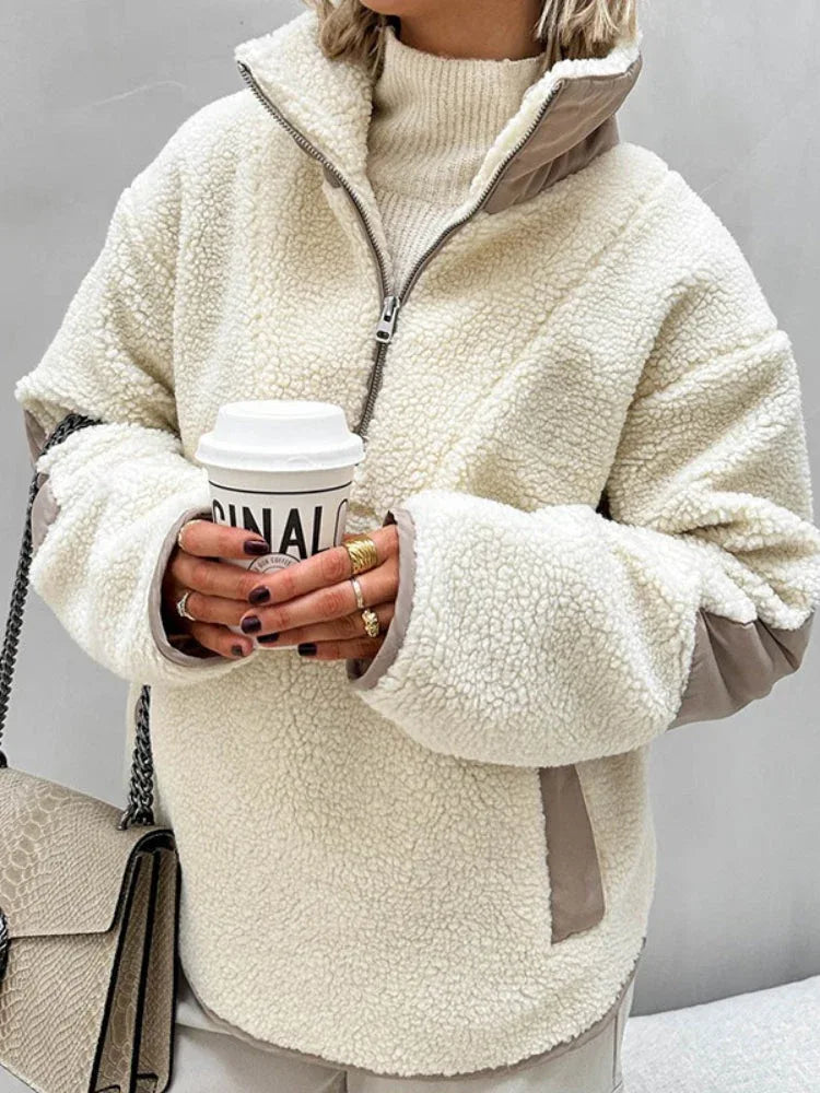 Woman holding a coffee cup while wearing a cream sherpa fleece quarter-zip pullover, showcasing the garment's texture and fit.