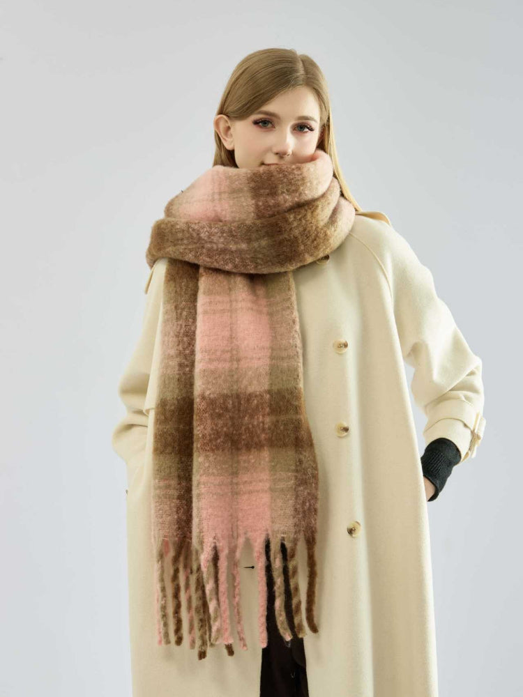Woman wearing a plaid scarf with pink and brown tones draped around her neck.