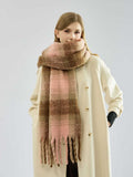 Woman wearing a plaid scarf with pink and brown tones draped around her neck.