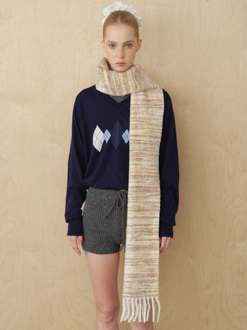 Model wearing a navy argyle V-neck sweater, grey knit shorts, and a striped scarf with fringe detail.