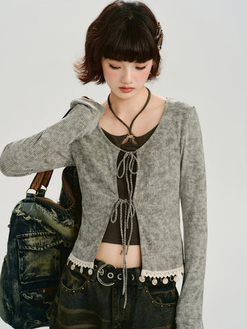 Woman wearing a grey ribbed knit tie-front cardigan with lace trim