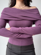 Woman wearing a purple off-the-shoulder ribbed knit top with long sleeves.