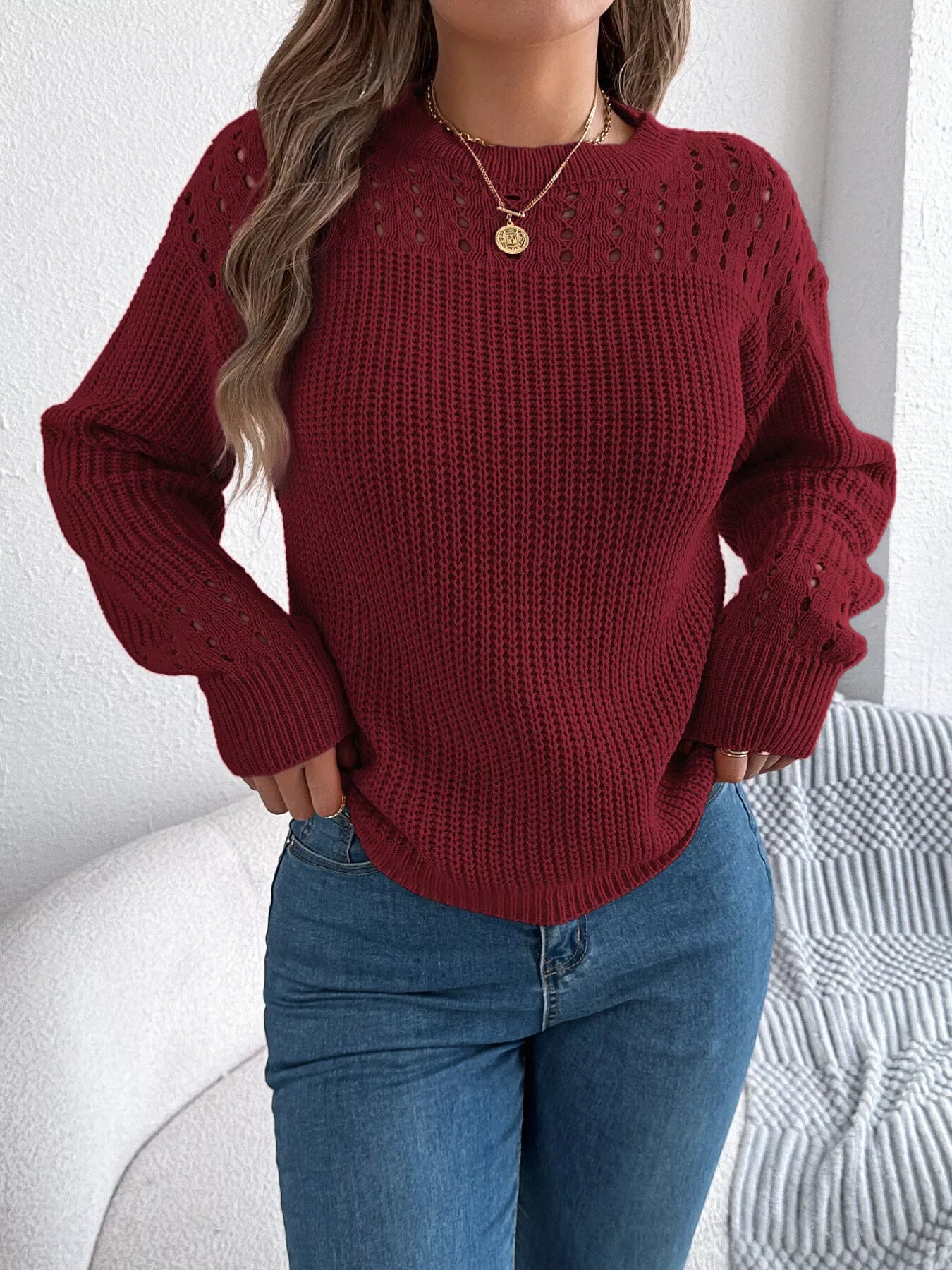 Woman wearing a burgundy knit sweater with crew neck and long sleeves.