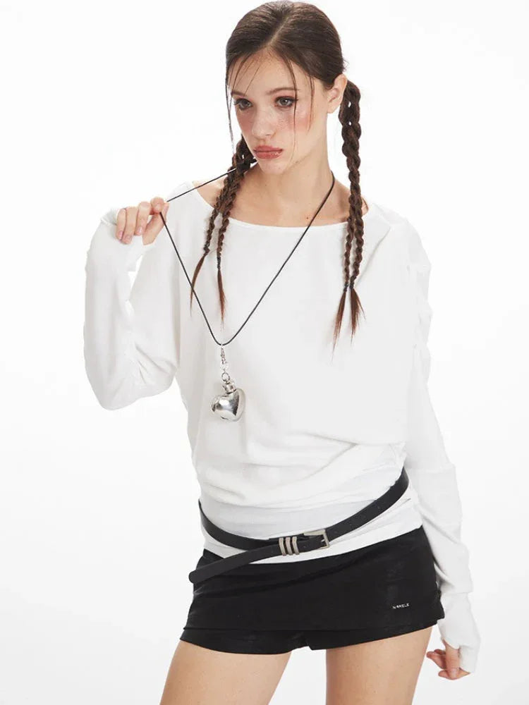 Model posing with a white long-sleeve top and black shorts, showcasing the neckline and necklace.