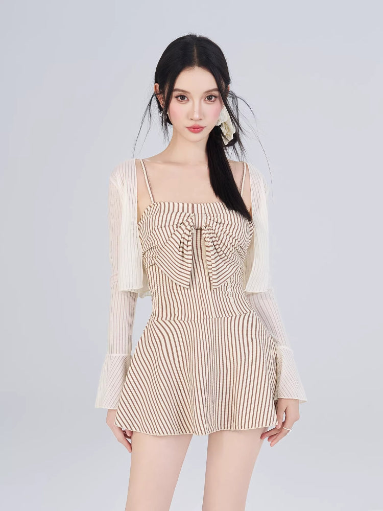 Woman wearing a striped fit and flare dress with a bow detail and a sheer overlay cardigan.