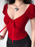 Close-up of a red velvet top with a tie front and ribbon detail